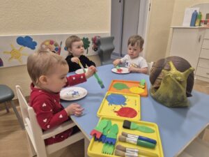 Dzieci malują farbami papierowy talerzyk, który będzie skorupą ślimaka.
