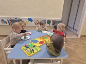 Dzieci malują papierowy talerzyk farbami.