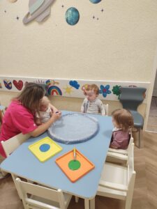 Ciocia pomaga dzieciom malować makietę Ziemi.