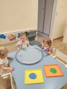 Dzieci malują makietę ziemi kolorem niebieskim i zielonym.