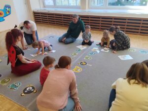 Dzieci wraz z rodzicami układają puzzle przedstawiające mieszkańców łąki