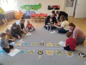 Dzieci wraz z rodzicami układają puzzle przedstawiające mieszkańców łąki