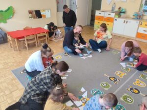 Dzieci wraz z rodzicami układają puzzle przedstawiające mieszkańców łąki