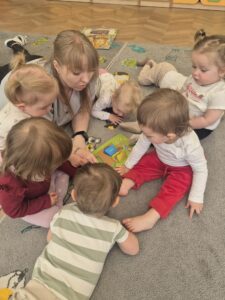 Dzieci wspólnie z ciocią poznają segregację. Czytamy co powinno znajdować się w odpowiednich pojemnikach do segregacji odpadów.