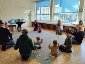 Dzieci wraz z rodzicami tańczą na dywanie