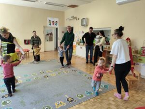 Dzieci wraz z rodzicami tańczą na dywanie