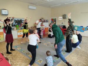 Dzieci wraz z rodzicami tańczą na dywanie