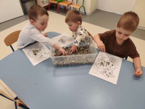Dzieci wyklejają szablon baranka baziami