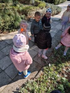 Dzieci szukają ukrytych kolorowych jajek w ogrodzie