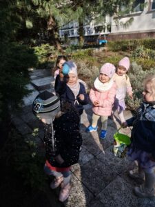 Dzieci szukają ukrytych kolorowych jajek w ogrodzie