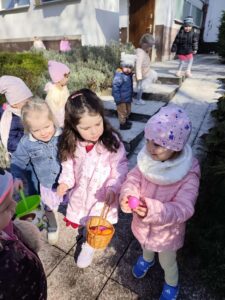 Dzieci szukają ukrytych kolorowych jajek w ogrodzie