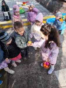 Dzieci szukają ukrytych kolorowych jajek w ogrodzie