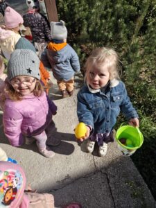 Dzieci szukają ukrytych kolorowych jajek w ogrodzie