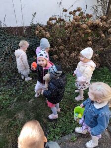 Dzieci szukają ukrytych kolorowych jajek w ogrodzie