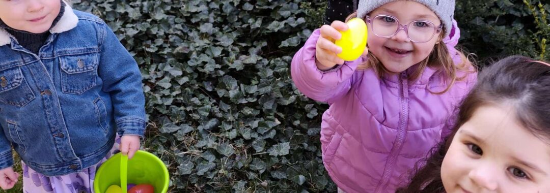 Dzieci szukają ukrytych kolorowych jajek w ogrodzie