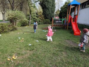 Dzieci na ogrodzie sprzątają śmieci i wkładają je do odpowiednich worków