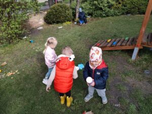 Dzieci na ogrodzie sprzątają śmieci i wkładają je do odpowiednich worków