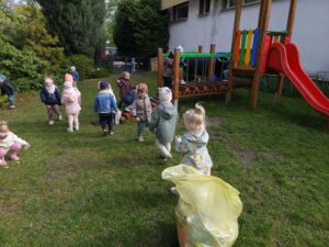 Dzieci na ogrodzie sprzątają śmieci i wkładają je do odpowiednich worków