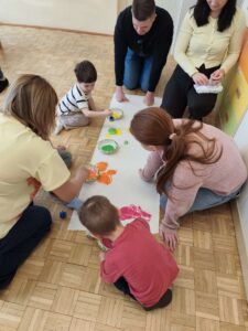 Dzieci wraz z rodzicami malują łąkę