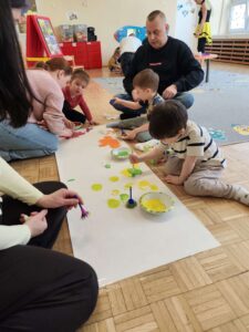 Dzieci wraz z rodzicami malują łąkę