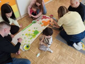 Dzieci wraz z rodzicami malują łąkę