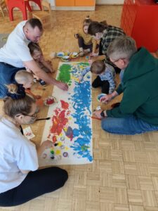 Dzieci wraz z rodzicami malują łąkę