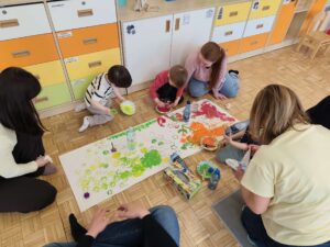 Dzieci wraz z rodzicami malują łąkę