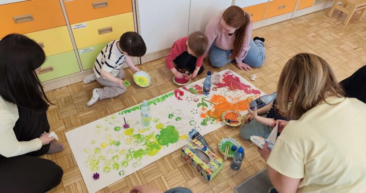 Dzieci wraz z rodzicami malują łąkę