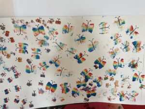 Dzieci tworzą motyle odbijając gąbkę pomalowaną farbą.