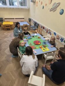 Dzieci wspólnie z rodzicami tworzą łąkę pełną kwiatów. malują farbami kwiatki na zielonym brystolu.