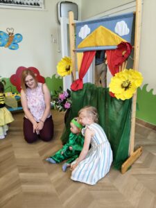 Dzieci robią sobie zdjęcia na tle ścianki. Chłopiec jest przebrany za żabę.