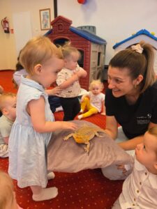 Dzieci podczas warsztatów przyrodniczych poznają agamę brodatą, obserwują ją z bliska i uczestniczą w zajęciach edukacyjnych w sali żłobkowej.