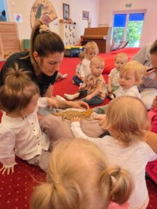 Dzieci podczas warsztatów przyrodniczych poznają agamę brodatą, obserwują ją z bliska i uczestniczą w zajęciach edukacyjnych w sali żłobkowej.