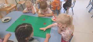 Dziewczynka odbija dłoń pomalowaną czerwoną farbą