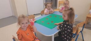 Dziewczynka odbija dłoń pomalowaną czerwoną farbą