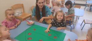 Dziewczynka odbija dłoń pomalowaną czerwoną farbą