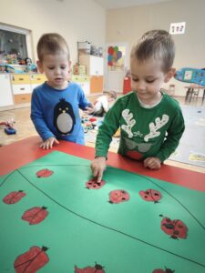 Chłopiec odbija palec umoczony w czarnej farbie na korpusie biedronki