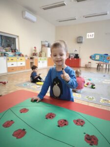 Chłopiec odbija palec umoczony w czarnej farbie na korpusie biedronki