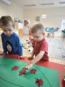 Chłopiec odbija palec umoczony w czarnej farbie na korpusie biedronki