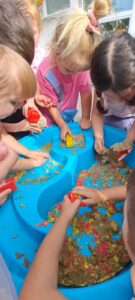 Dzieci bawią się piaskiem kinetycznym w ogrodzie