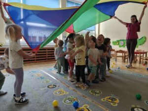 Dzieci wraz z opiekunami bawią się chustą animacyjną