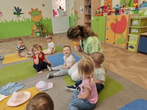 opiekun pokazuje krem z filtrem i tłumaczy dzieciom kiedy się go używa