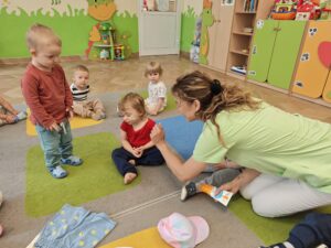 opiekun pokazuje krem z filtrem i tłumaczy dzieciom kiedy się go używa