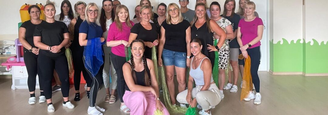 Kadra żłobka bierze udział w szkoleniu muzycznym, bawiąc się kolorowymi chustami i apaszkami.