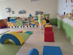 Chłopiec przechodzi po wysokiej przeszkodzie. Ciocia trzyma go za rękę.