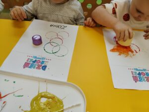 Chłopiec odbija okrągły wzór tworząc kropki na kartce.