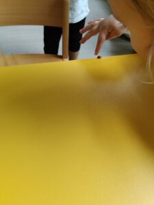 Dzieci podziwiają biedronkę, którą znaleźli w woreczku z liśćmi przyniesionymi ze spaceru.