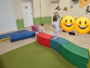 Dzieci obserwują jak koleżanki i koledzy pokonują tor przeszkód.