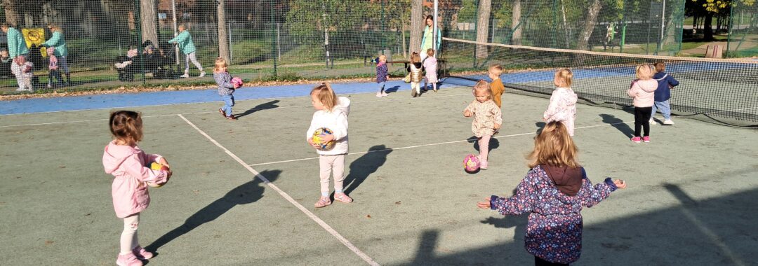 Dzieci bawią się piłkami na korcie tenisowym