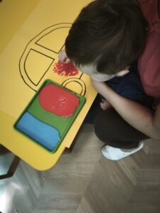 Dziecko maluje dłonią narysowany samochód.